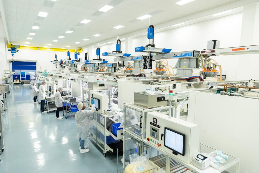 Interior production floor at the Borgman Industrial facility, with white-suited workers operating automated pick-and-place manufacturing equipment