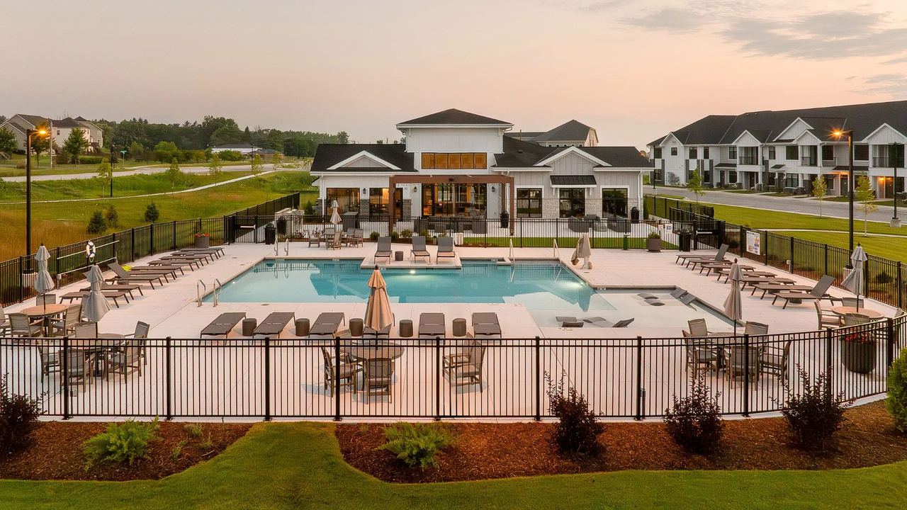 Pool and clubhouse amenity area at FRED Seasons at dusk, with lounge seating around the pool and the clubhouse building in the background
