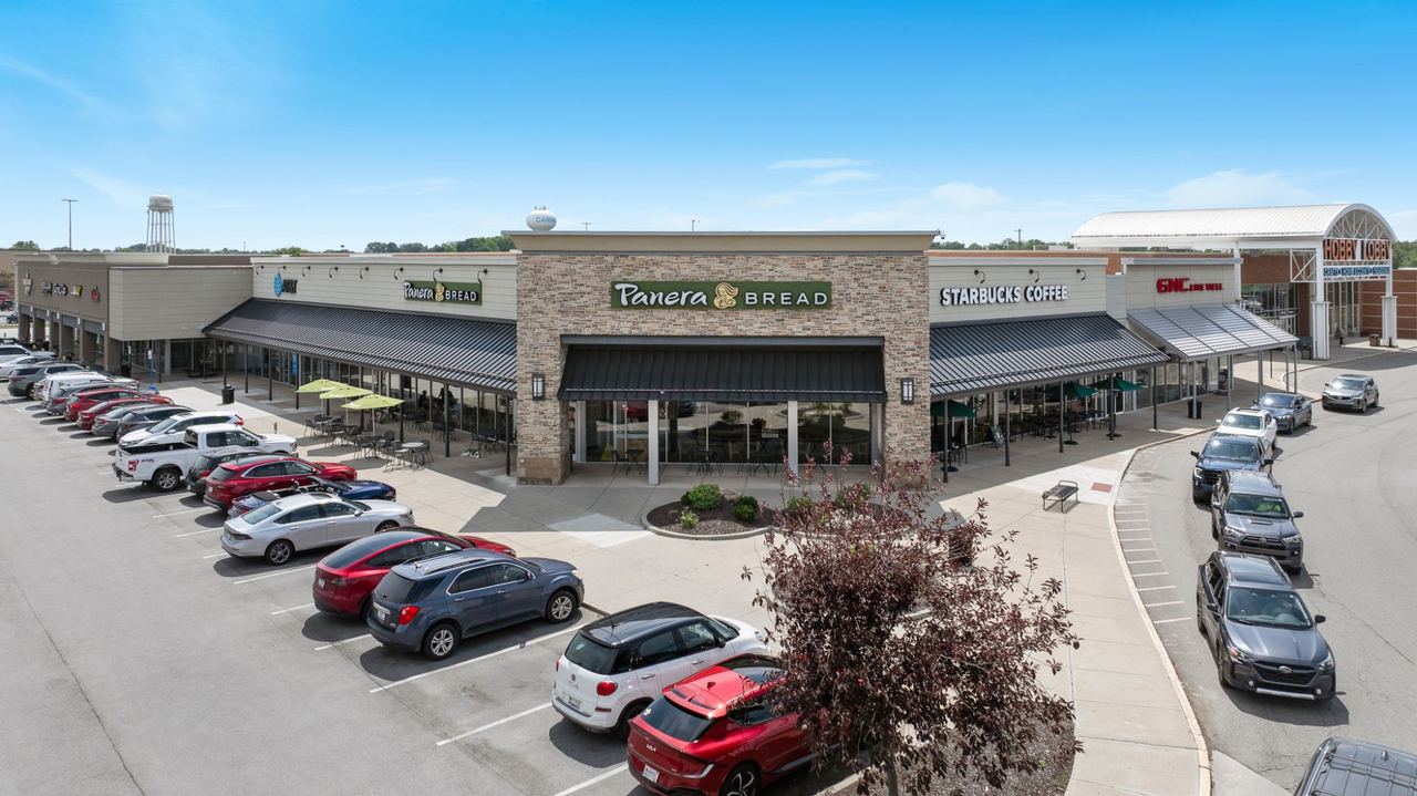 Village Park Plaza retail shopping center exterior with Panera Bread, Starbucks, GNC, and Hobby Lobby storefronts